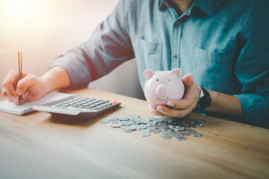 man counting pennies with piggy bank